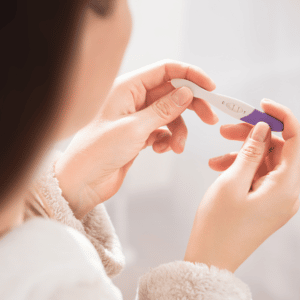 mulher branca vista de cima segurando um teste de gravidez em suas mãos