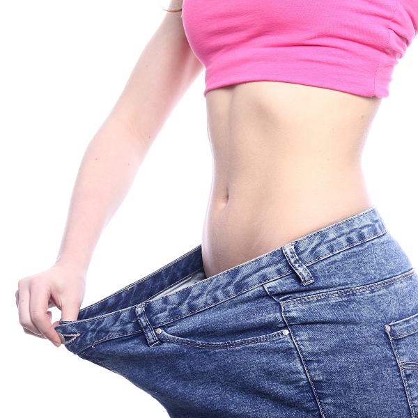 Close em barriga feminina com calça larga sendo puxada