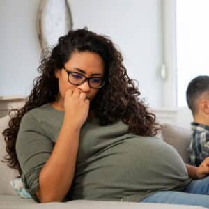 mulher gravida sentada no sofá roendo as unhas em ansiedade